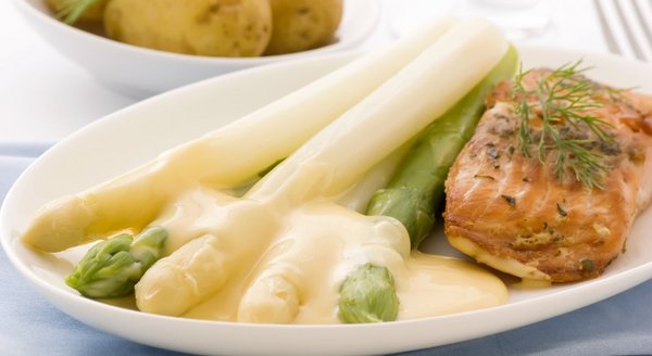 Teller angerichtet mit einem traditionellen Frühlingsgericht aus grünem und weißem Spargel, Sauce Hollandaise und Lachs.