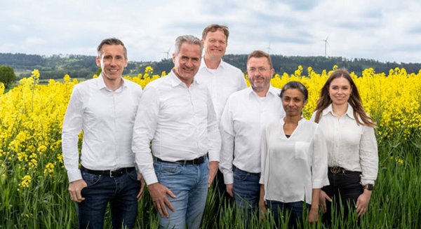 Die Führungspersonen vor RAPS stehen aufgereiht vor einem Rapsfeld.