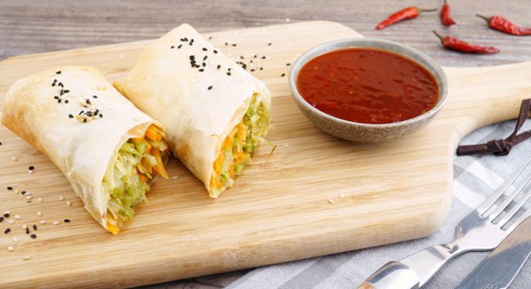 Asiatische Frühlingsrolle mir roter Sauce auf einem Brett 